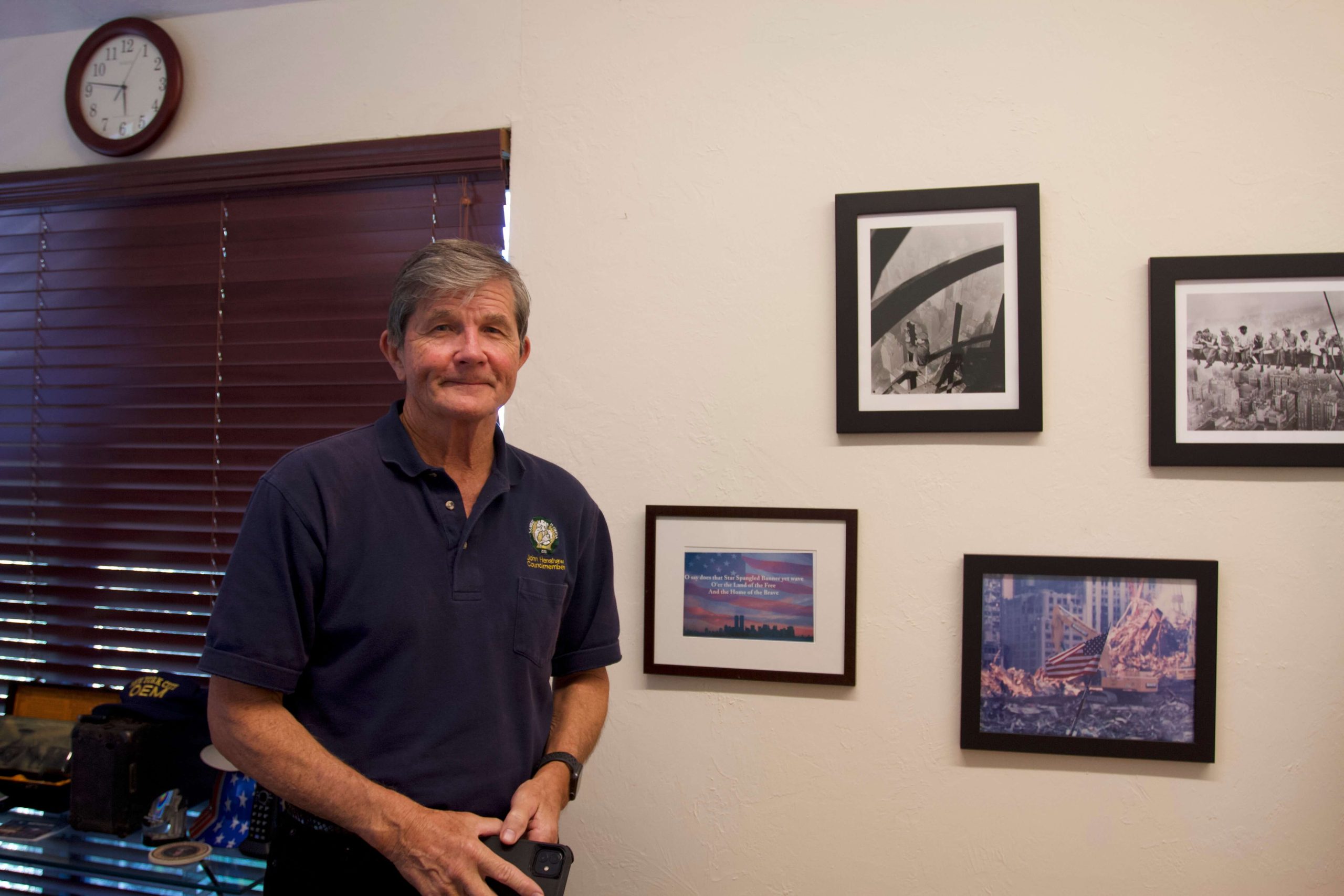 John Henshaw stands next to a photo gallery of 9/11 photos on the wall. (Janelle Retka / Columbia Journalism Investigations)