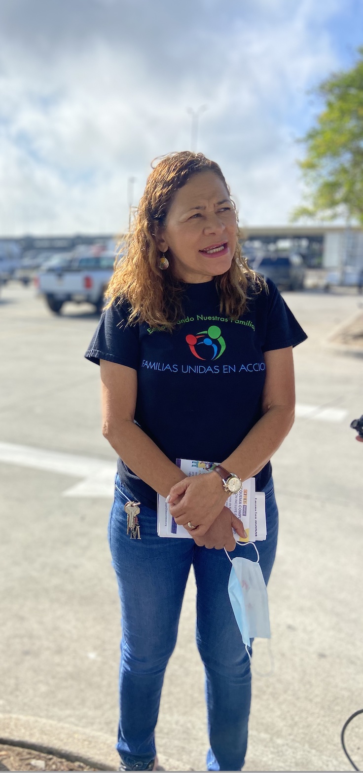 Miriam Romero, a community health worker with Familias Unidas en Acción, wears the organization’s navy T-shirt and jeans, and speaks with disaster restoration workers while holding leaflets and a mask. Romero handed out free NIOSH-approved masks and leaflets on workplace toxins to day laborers waiting for a job in a Lowe’s parking lot in New Orleans. (María Inés Zamudio/ Center for Public Integrity)